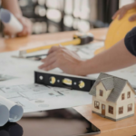 Projekt domu modułowego na biurku z miarką, poziomicą i modelem domu, symbolizujący wybór metrażu 35, 50 lub 70 m².